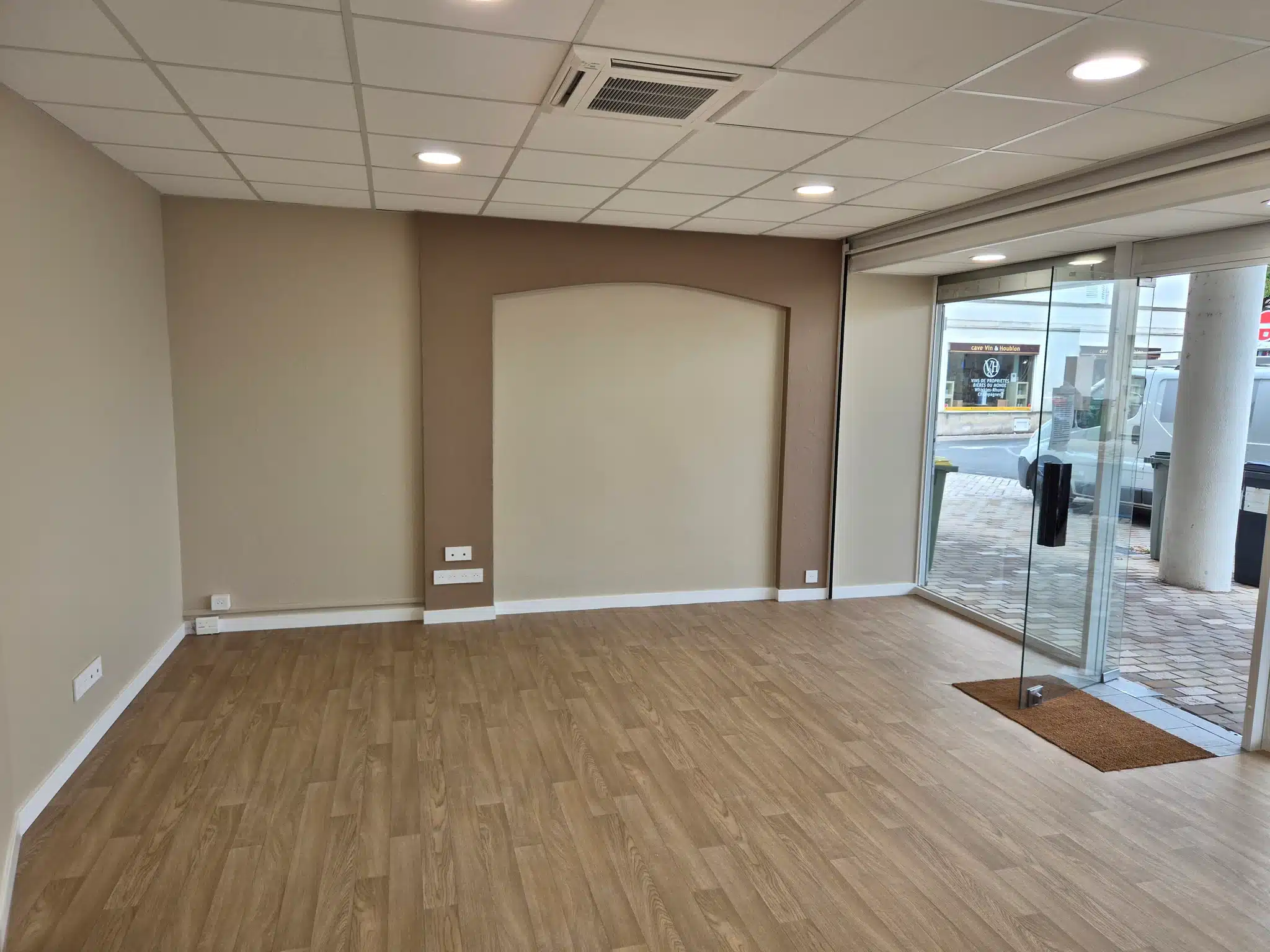 Local commercial repeint avec mur d'accent taupe et sol souple effet bois