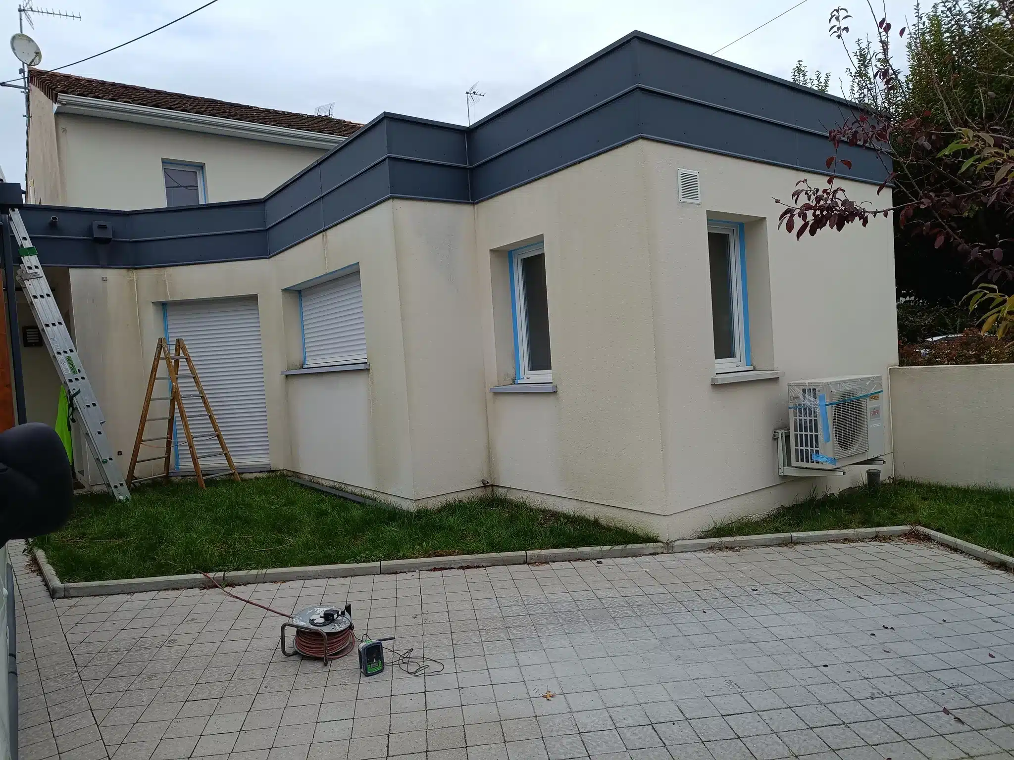 Façade de maison repeinte en ton crème avec bandeau gris anthracite